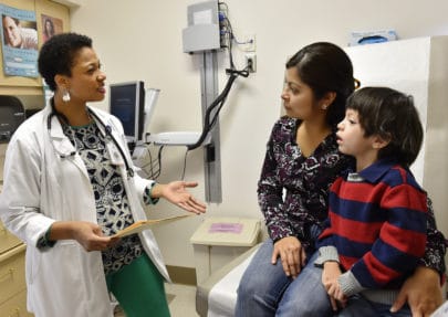 Photo of a doctor talking to a mother and her child.